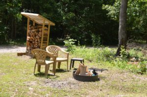 fire pit with chairs and stacked firewood